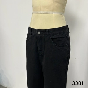 Detailed close-up of black tencel denim fabric texture and silver button on business jeans