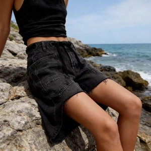 Detail of black washed denim shorts featuring cargo pockets and drawstring waist design
