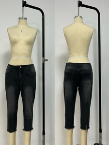 Detail of washed grey slim-fit cropped jeans with distressed raw hem and classic five pockets