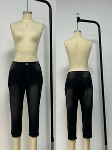 Detail of grey washed denim capris with frayed hems and classic five-pocket design