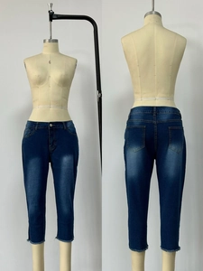 Detail of dark blue stretch denim pants featuring frayed hems and vintage washed finish