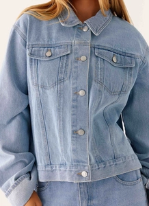 Gros plan sur la veste en jean bleu clair avec col classique et poches à rabat