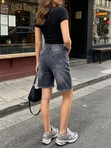 Dettaglio ravvicinato di pantaloncini in denim grigio scuro lavato con orlo a taglio vivo