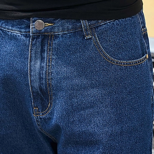Close-up of denim shorts featuring vintage metal button and orange contrast stitching