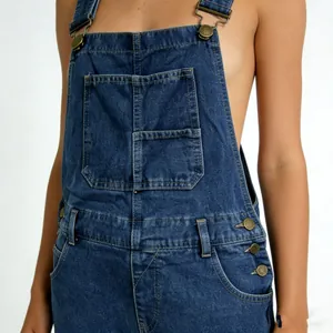 Détail d'une salopette en jean bleu foncé avec poche avant et boucles métalliques réglables
