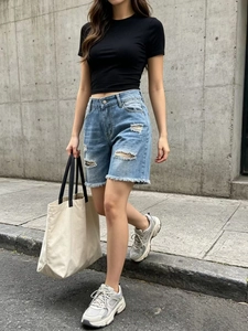 Outfit estivo da donna con maglietta nera slim e pantaloncini di jeans azzurri strappati