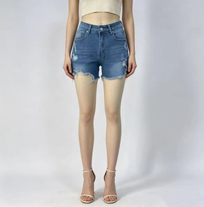 Détail de l'ourlet effiloché et texture denim délavé sur le short à taille haute