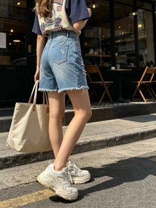 Dettaglio degli shorts in denim azzurro a vita alta con strappi e orli sfrangiati