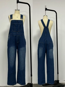 Detail view of dark blue denim overalls with adjustable metal buckles and washed finish