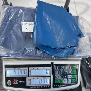 Detailed view of folded denim overalls in size S being weighed on a scale for shipping