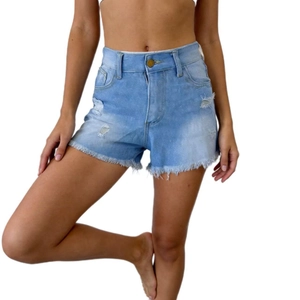 Macro detail of high-waisted light blue denim shorts with ripped holes and frayed raw hems