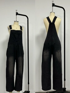 Detail view of washed black denim overalls showing metal buckles and vintage texture