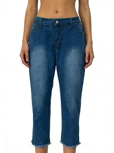 Close-up of dark blue washed denim jeans with whisker details and frayed raw hem