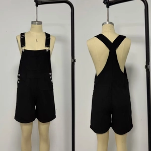 Detail of black denim overalls with metal side buttons and X-shaped back straps