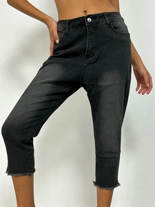 Detail view of the raw hem and washed charcoal gray texture of these stretch denim pants