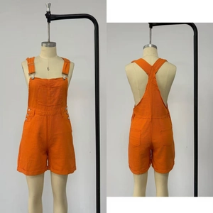Detail of bright orange dungaree shorts showing metal buckles and cross-back straps