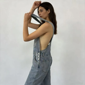 Vue détaillée de la salopette en jean bleu clair montrant le design creux et les boutons