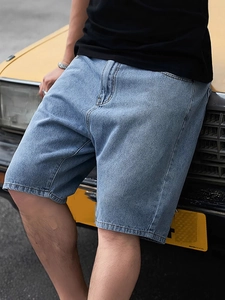 Men's light blue casual straight denim shorts on a model posing by a yellow vintage car