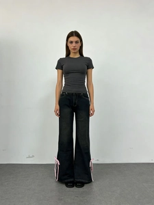 Dettaglio di fiocchi in nastro rosa sull'orlo laterale dei jeans a gamba larga a vita alta