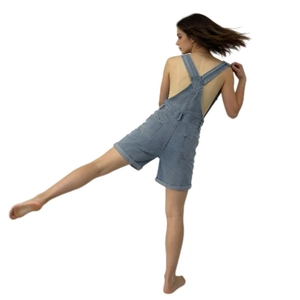 Back view of light blue denim overalls showing cross straps and rear dual pockets