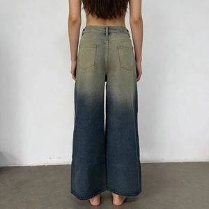 Detail of high-waisted wide-leg jeans featuring vintage blue to yellow ombre wash effect
