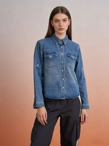 Detail of washed blue denim shirt featuring classic front double pockets and button closure