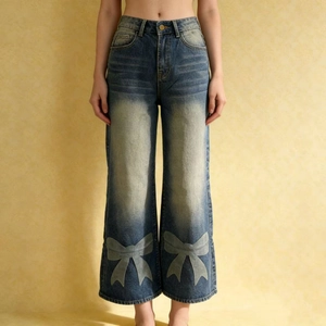 Detailed view of blue wide leg jeans with bow prints and washed denim texture