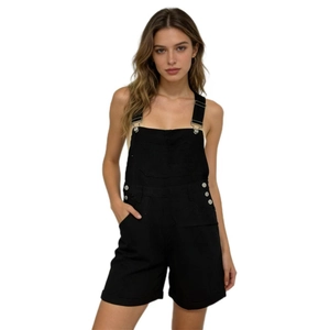 Detail view of adjustable metal buckles and chest pocket on black denim overalls
