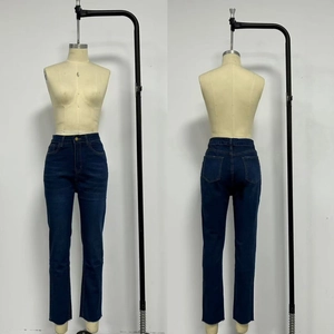 Détail du jean taille haute bleu foncé avec ourlet brut et texture denim classique