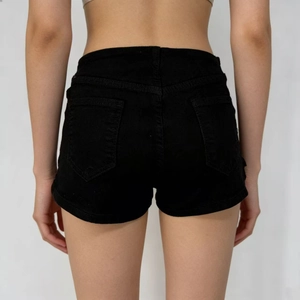 Detail shot of black high-waisted denim shorts featuring back pockets and hem stitching