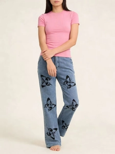 Détail d'un jean bleu clair à jambe droite orné d'imprimés papillons noirs pour femme