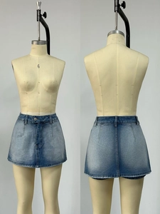 Dettaglio minigonna in denim lavaggio azzurro con orlo a frange e motivi sbiaditi alla moda