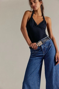 Dettaglio dei jeans a righe vintage a vita alta con cintura in pelle nera e fibbia decorata