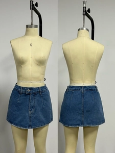 Dettaglio della gonna di jeans a trapezio a vita alta con orlo sfrangiato blu lavato