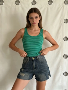 Women's summer green striped tank top paired with distressed raw hem denim shorts