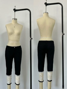 Détail du pantalon capri en jean noir extensible avec ourlet en dentelle florale blanche élégante