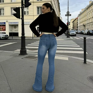 Street style view of high waisted washed flare jeans with faded details from the back