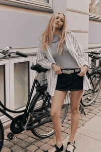 Minigonna di jeans alla moda abbinata a camicia a righe e cintura in una scena urbana