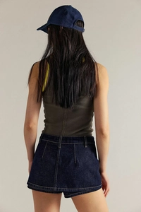 Vista posteriore di una modella con canotta a coste verde oliva e minigonna di jeans blu