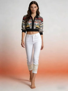 Close-up of stylish white cropped jeans featuring elegant floral lace patchwork hem