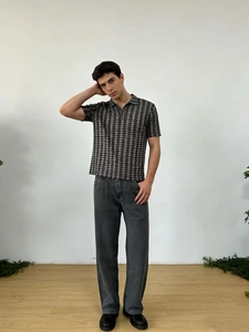 Vue complète du jean droit gris délavé pour homme avec polo noir à motifs géométriques