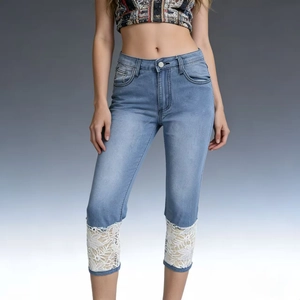 Detail of light blue denim pants featuring elegant white floral lace patchwork at the hem
