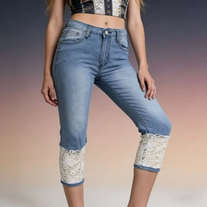 Detailed view of white floral lace patchwork on light blue cropped denim jeans