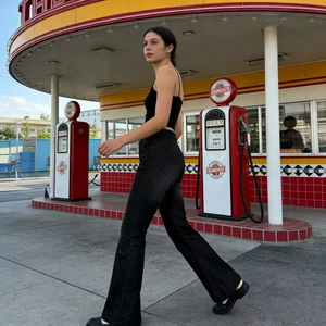 Outdoor street shot of women in vintage black high-waisted flared jeans and tank top