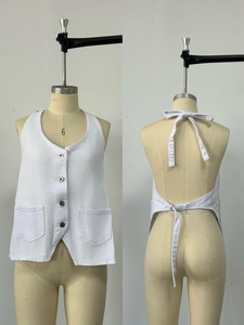 Detail of white halter denim vest with four-button front and back tie design