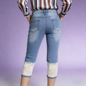 Detail of light blue denim capri pants with white crochet lace floral hem decoration