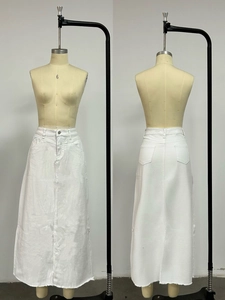 Detail view of white denim maxi skirt featuring raw hem edge and classic pocket styling