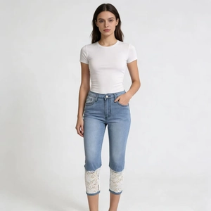Close-up of white floral lace hem on light blue slim fit cropped denim jeans
