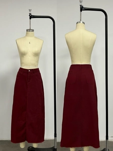 Detail of high waist burgundy denim maxi skirt with button closure and raw hem finish