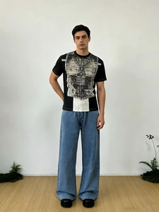Gros plan sur un jean bleu clair pour homme associé à un t-shirt noir au style rétro